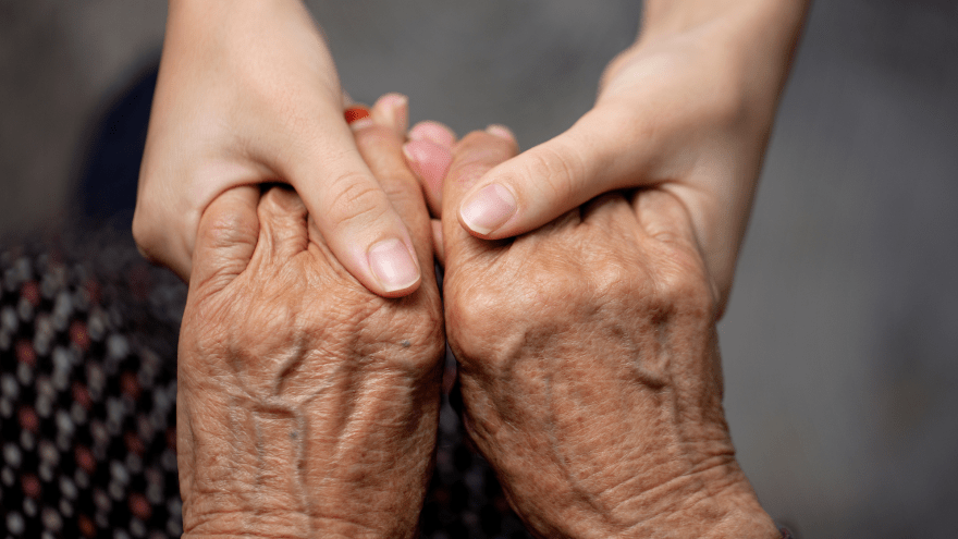 junge Hände halten fürsorglich die Hände einer alten Person